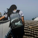 woman walking at bridge wearing backpack