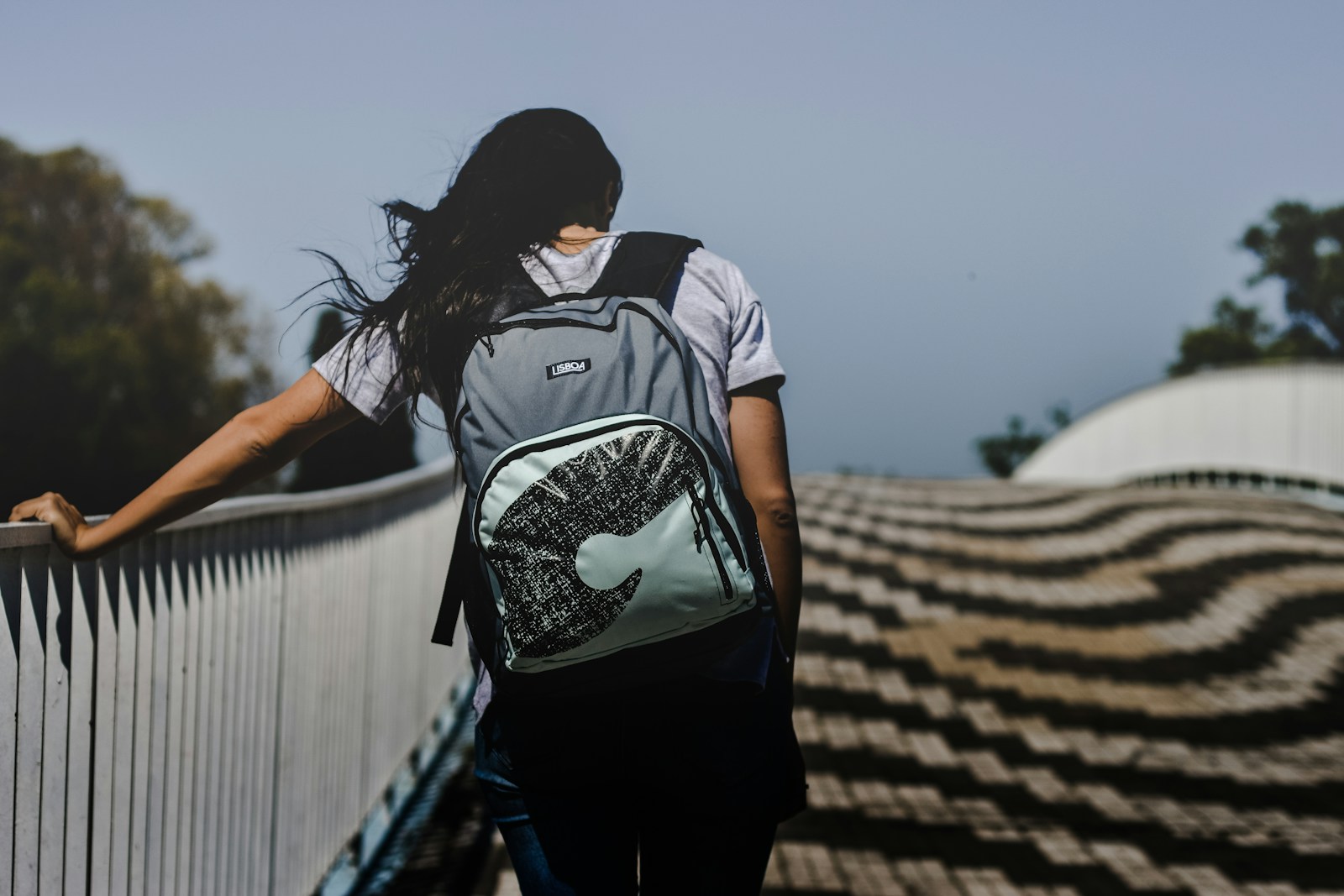 woman walking at bridge wearing backpack
