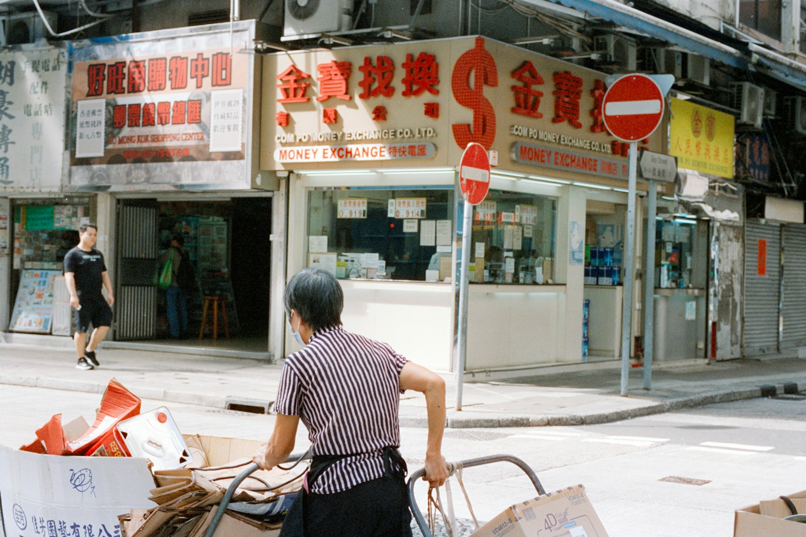 Person pushes cart past a pawn shop in city.