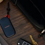 Portable ssd, keys, and pen next to a black bag.